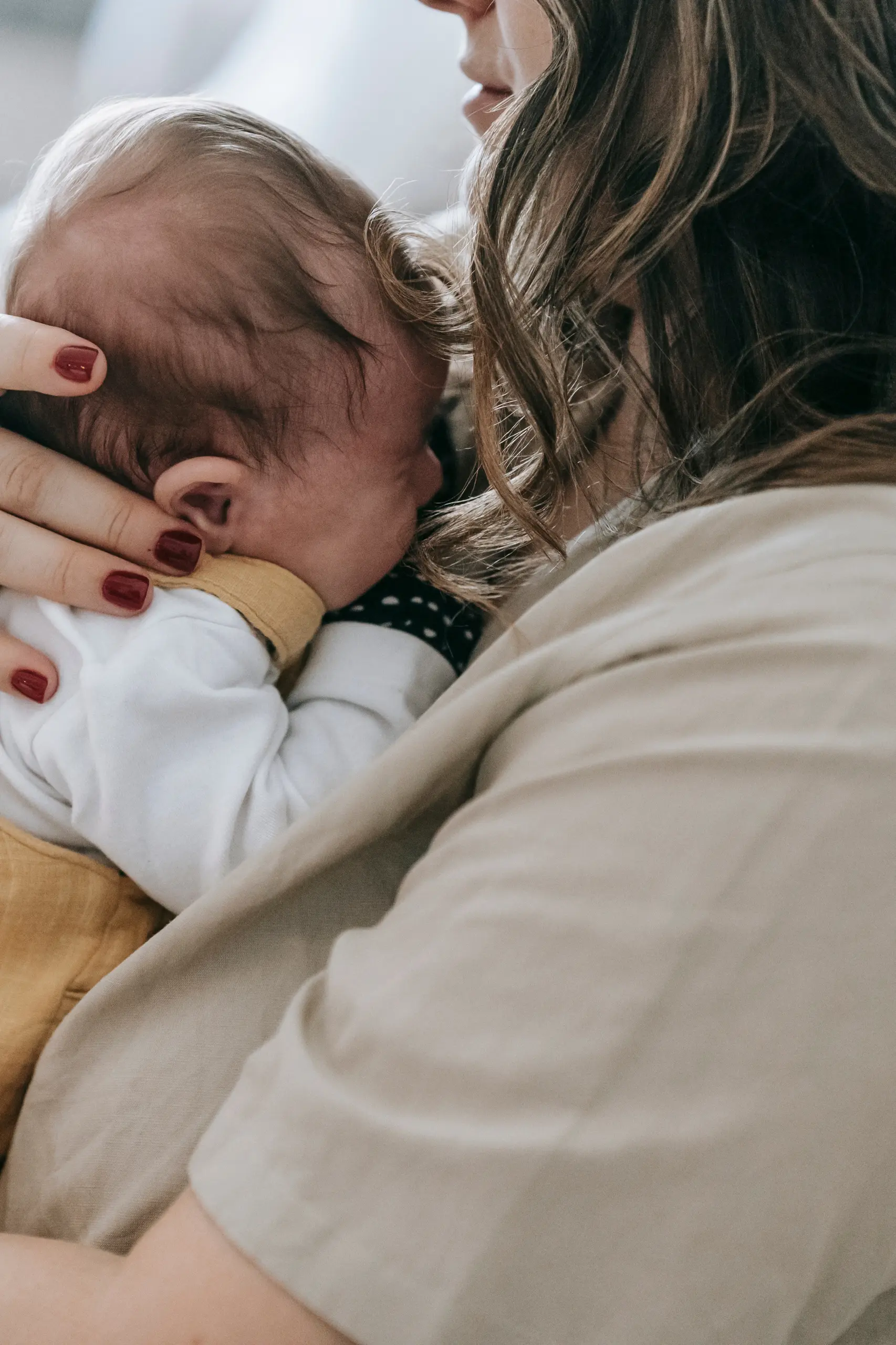 Mutter hält ihr Neugeborenes im Arm während der Wochenbettbetreuung